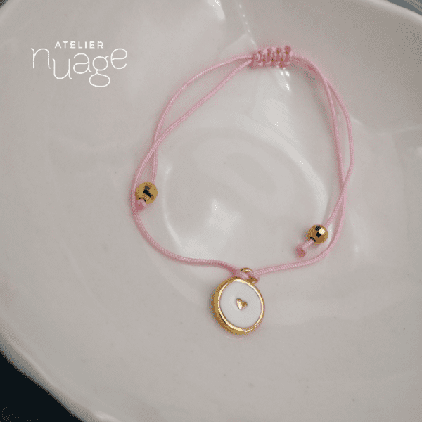 bracelet coulissant rose pâle et breloque dorée blanche avec petit cœur doré au centre