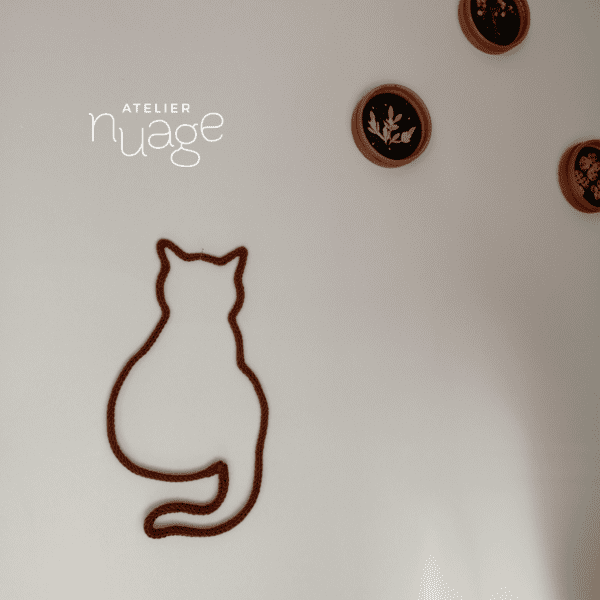 zoom sur chat en tricotin, accroché au mur