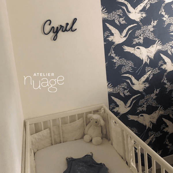 tricotin Cyril accroché dans une chambre d'enfant, lit à barreaux en dessous